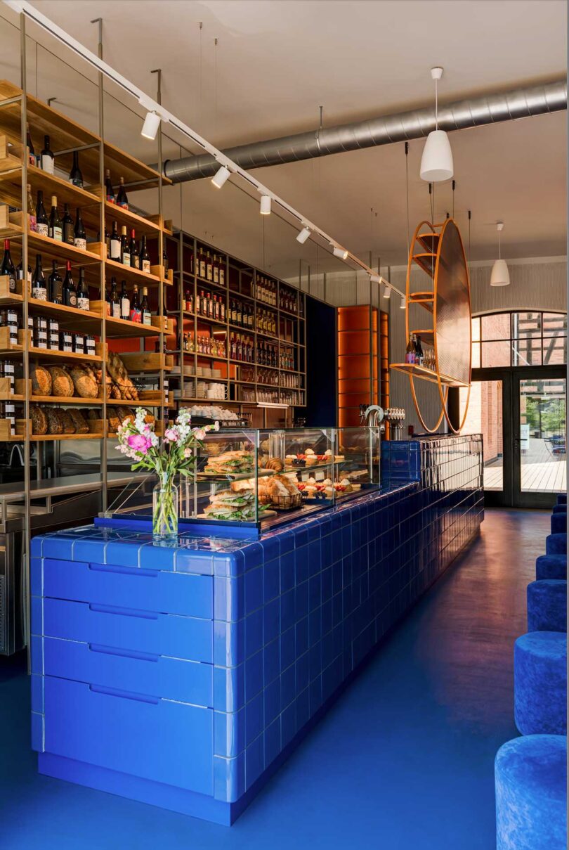 angled view of commercial restaurant interior with modern aesthetic featuring blue tiled counter and pastries stacked on shelving