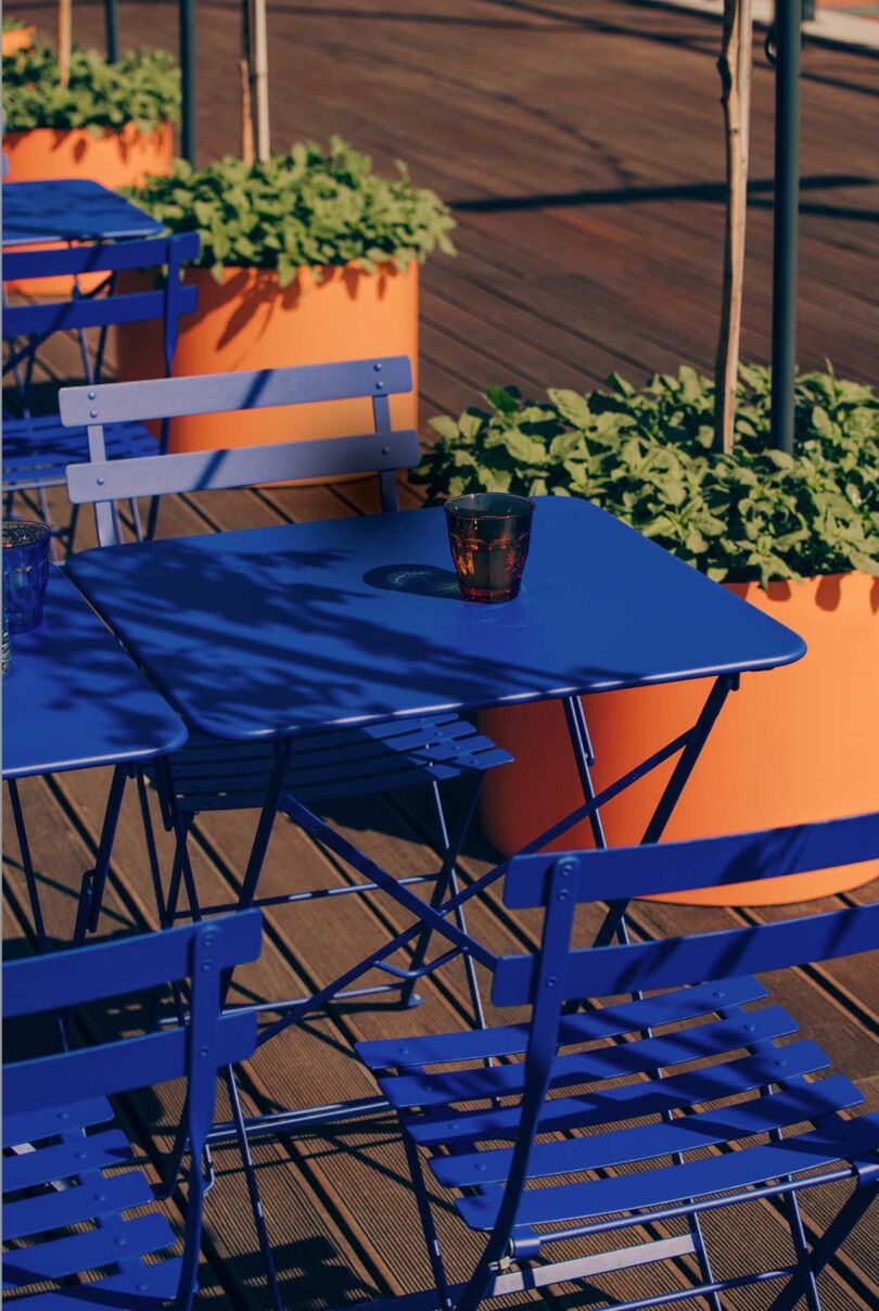 angled down shot of closeup of cobalt blue patio tables with plants in terracotta pots surrounding