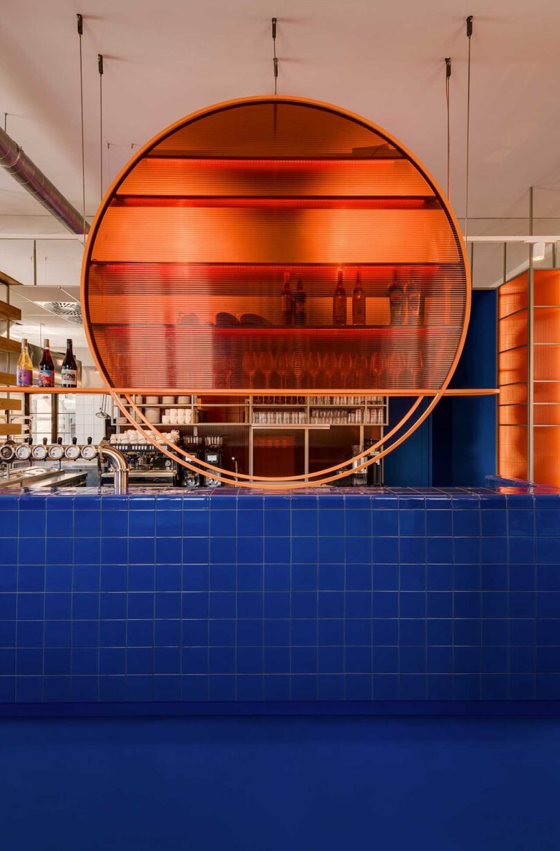 commercial restaurant interior with modern aesthetic featuring blue tiled counter and orange glowing circular shelf