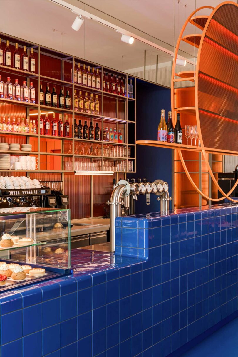 angled commercial restaurant interior with modern aesthetic featuring blue tiled counter and pastries stacked on shelving