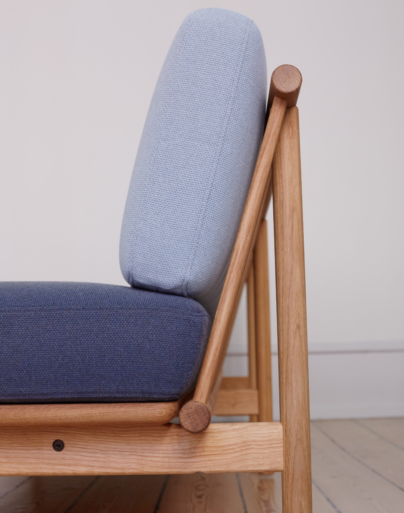 A side on view of the spoke sofa upholstered in two shades of blue/grey