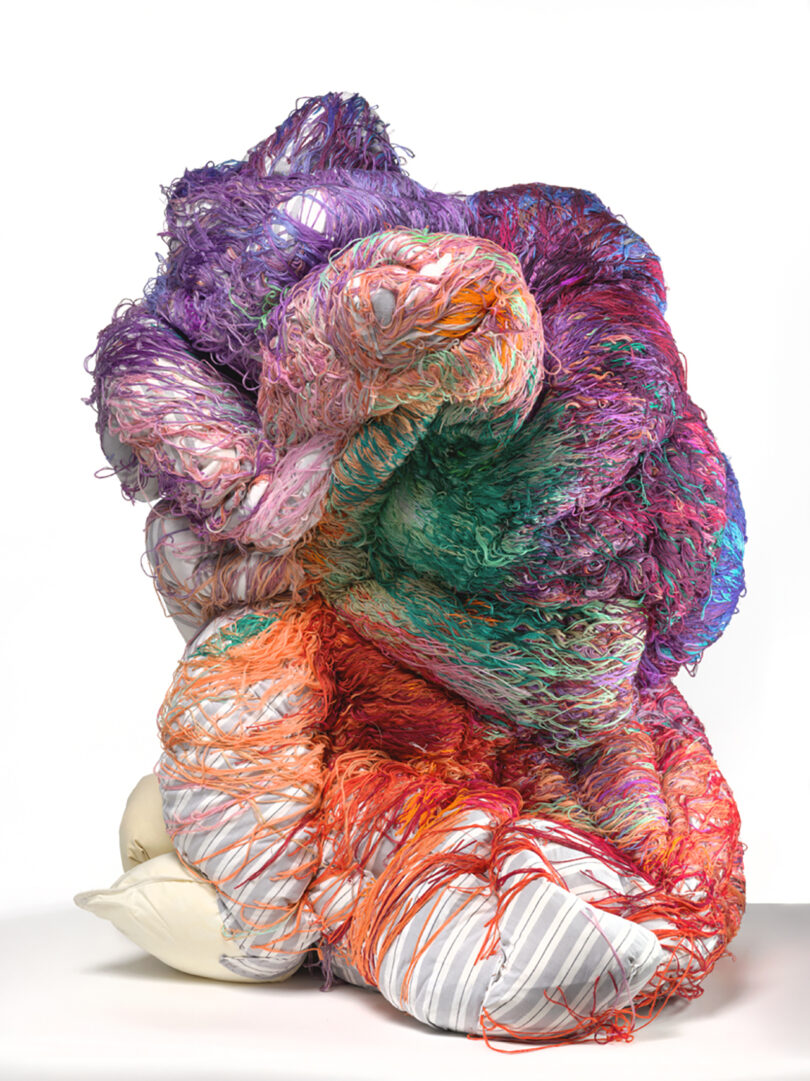 abstract sculpture covered in a rainbow of yarn