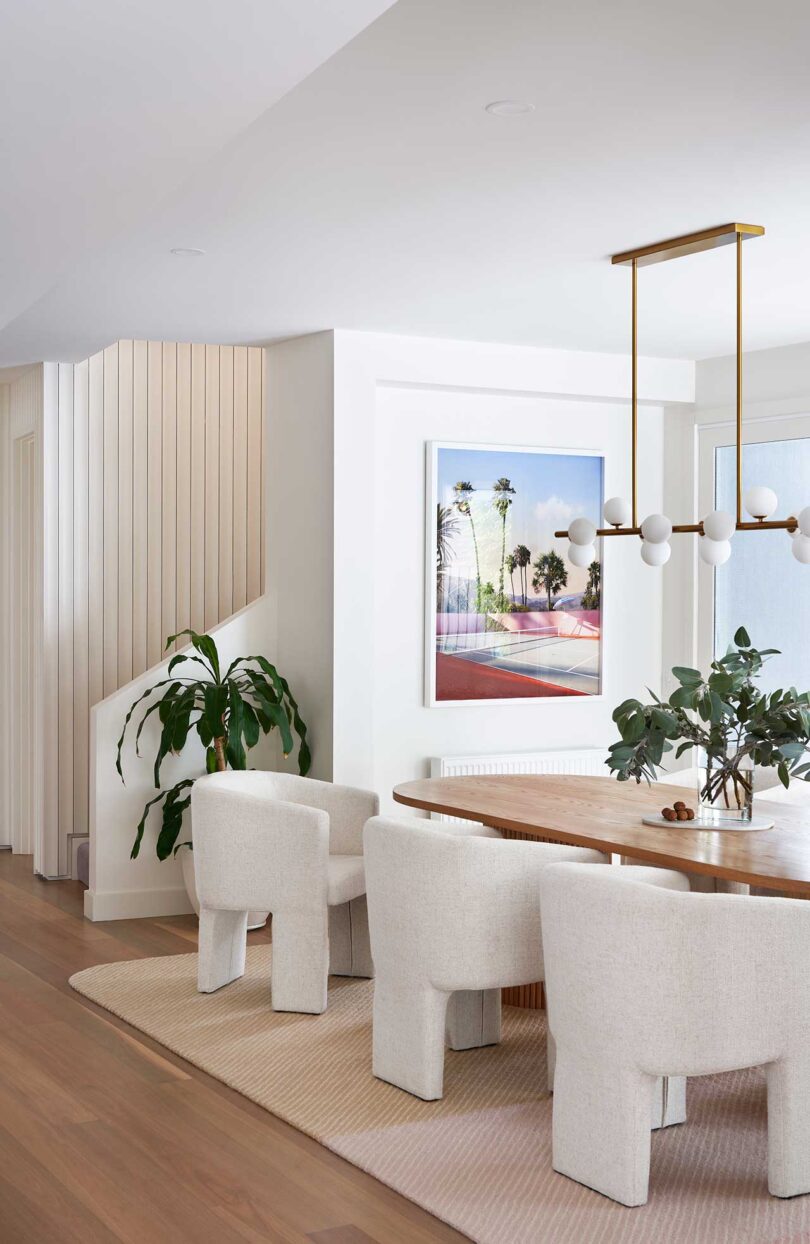 Angled interior view of modern dining room with wood table and white upholstered chairs