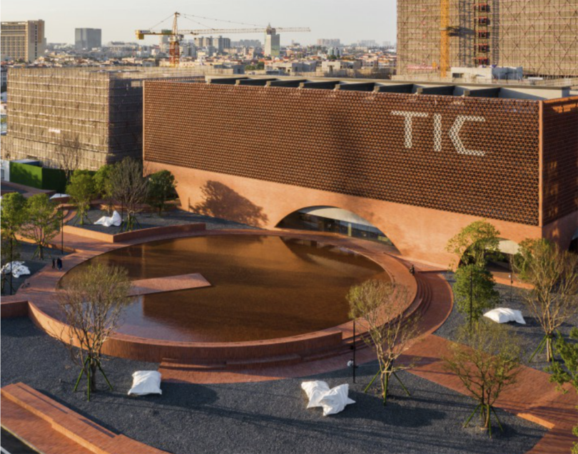 commercial building reading TIC on the exterior with a large round reflecting pool in front of it