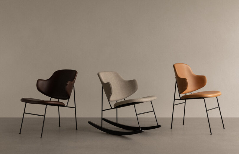 Three versions of the Penguin Chair by furniture designer Ib Kofod-Larsen; first chair is a dining chair with dark brown leather upholstery, middle chair is Penguin Rocker in tan boucle with black rockers, and third on the right is a dining chair with baseball glove tan leather upholstery