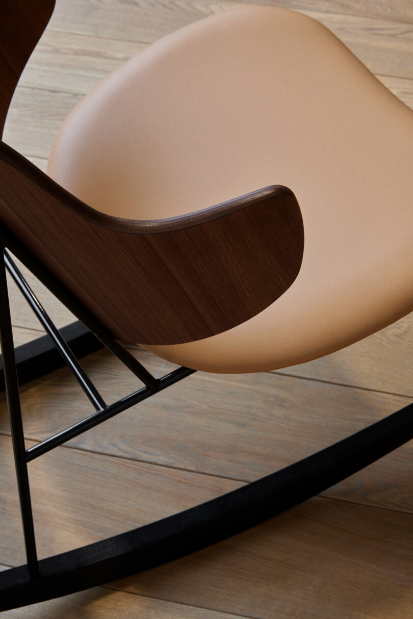 Overhead angled shot of the curved walnut wood back of the Penguin Rocker Chair, with light caramel leather seat.