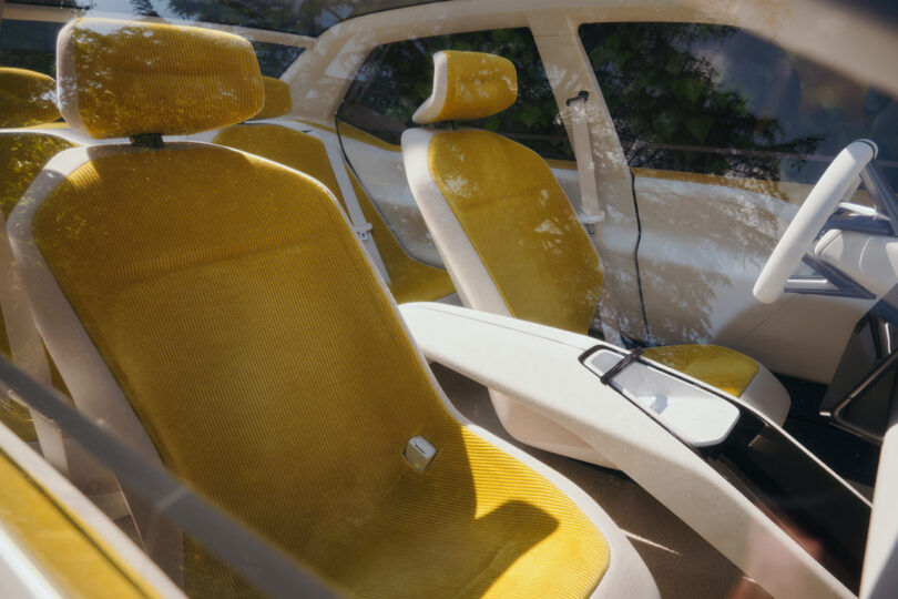 View staring into front passenger side of the BMW Vision Neue Klasse concept, with detail of the seats mustard yellow corduroy upholstery and large floating arch center console armrest.