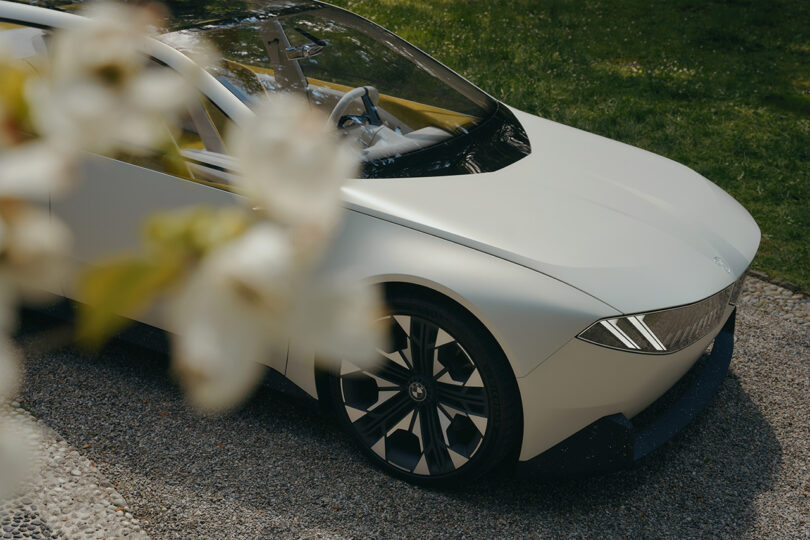 Front end of BMW Vision concept in white, with plant flowers obfuscating the rear half of the white EV.