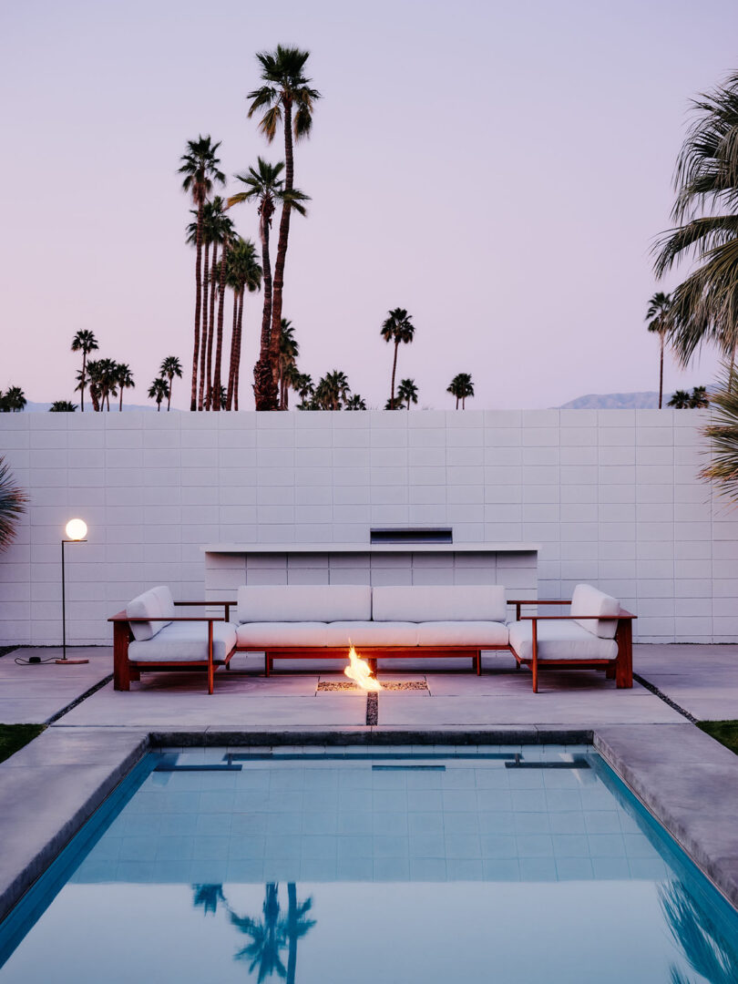 wood framed outdoor sofa with white upholstery in front of a pool