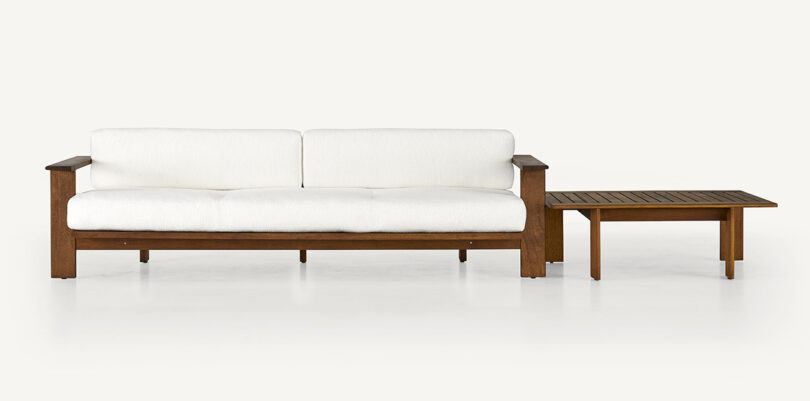 wood framed outdoor sofa with white upholstery and a square wood table
