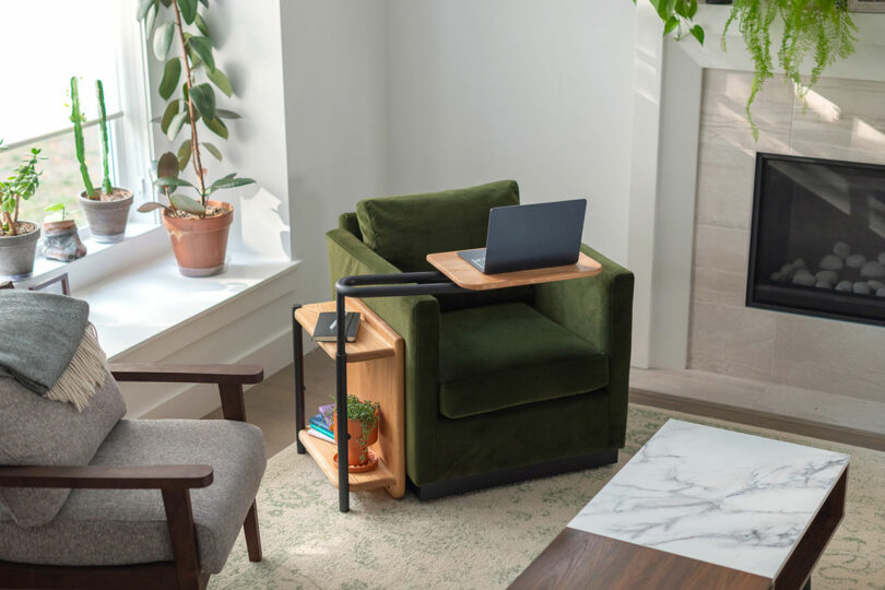 angled down view of narrow wood and black metal side table with rotate tabletop holding laptop over green chair
