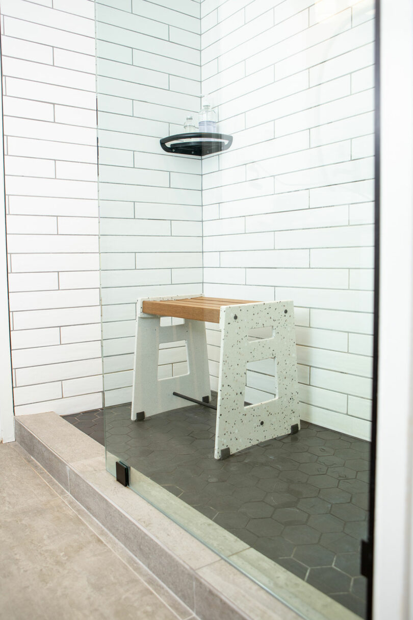angled view into white tiled shower with modern shower seat