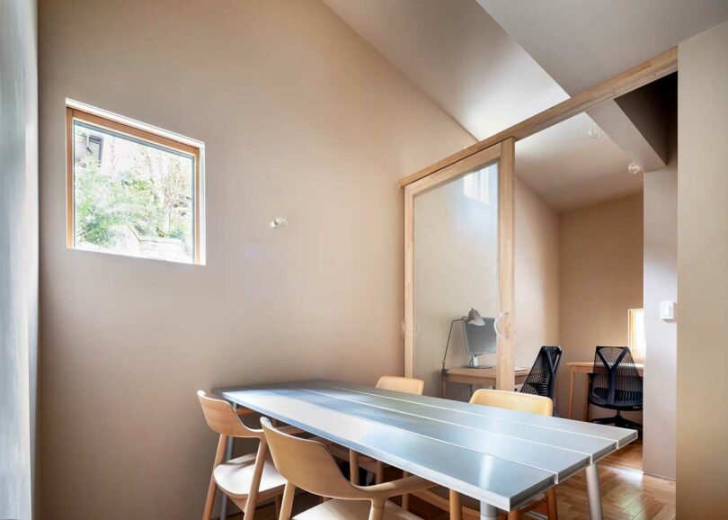 angled interior view of modern table with chairs and office behind it