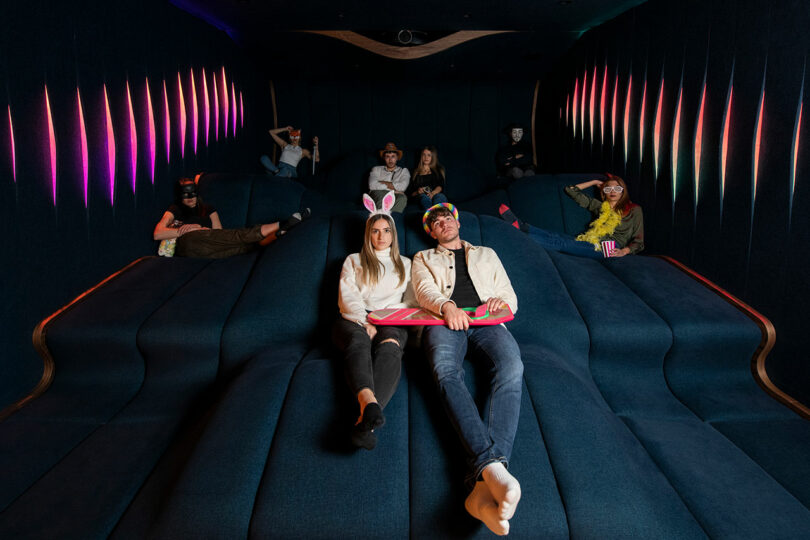 view in home cinema with waves of dark blue seating and people sitting randomly
