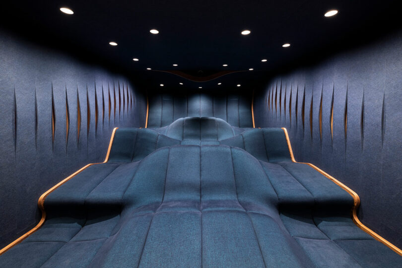 front view of modern home theater looking out to single undulating dark blue seating block
