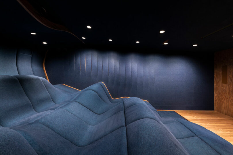 view of modern home theater looking out to single undulating dark blue seating block
