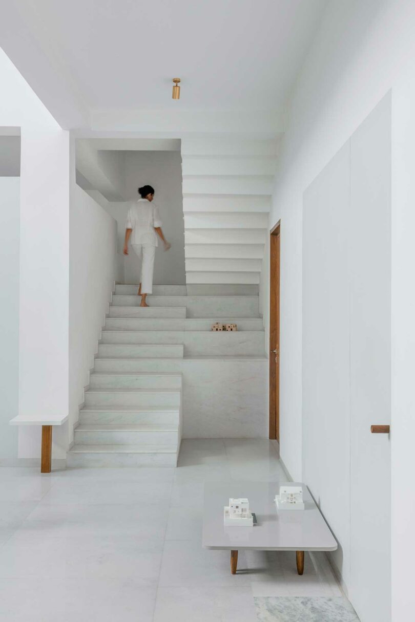 all white interior with white staircase with person walking up