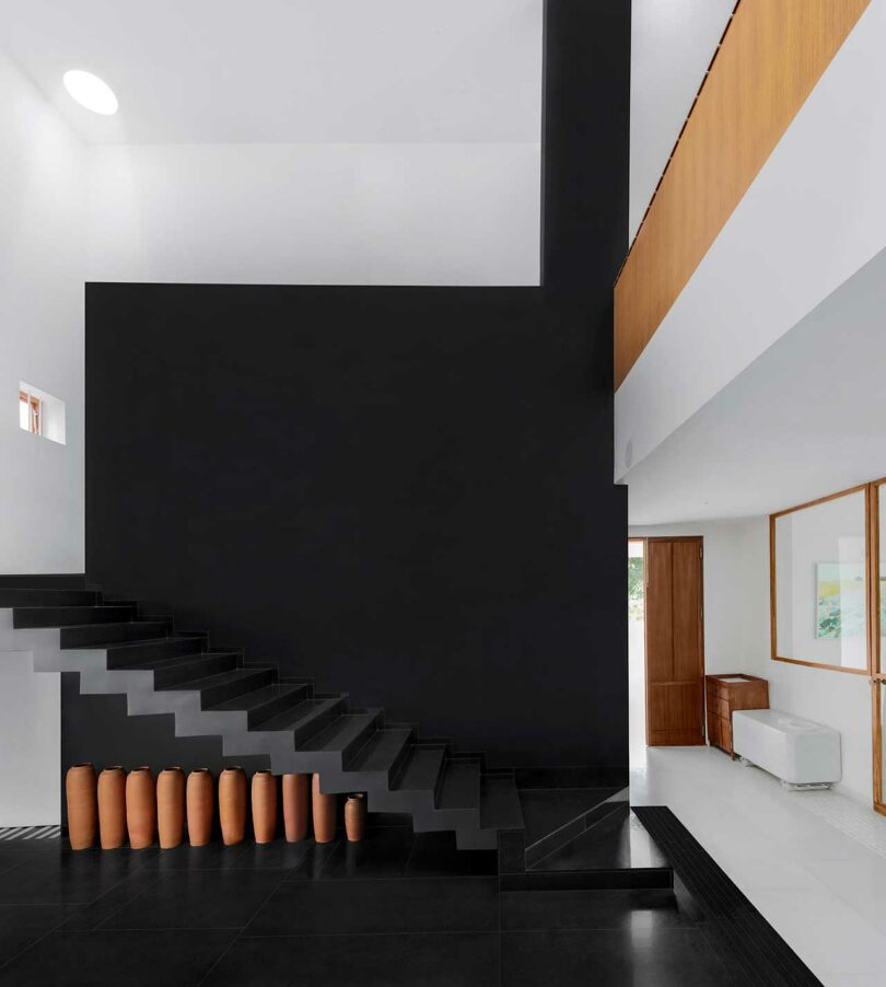 partial view of modern interior with black wall with black floating staircase