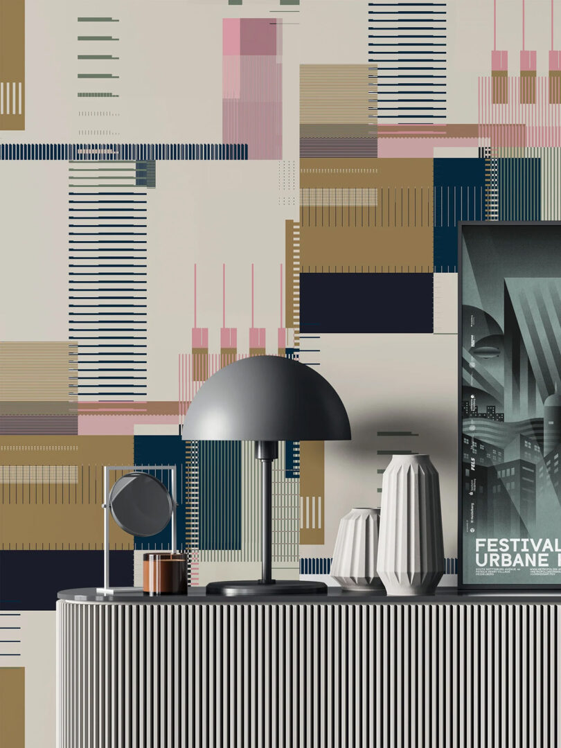 Jupiter 10 Glitch pink, beige, gray and black wallpaper staged in living room with long fluted console with small half-domed table lamp in matte gray, a pair of modern vases, and a cropped framed graphic poster promoting a festival peeking from the left.