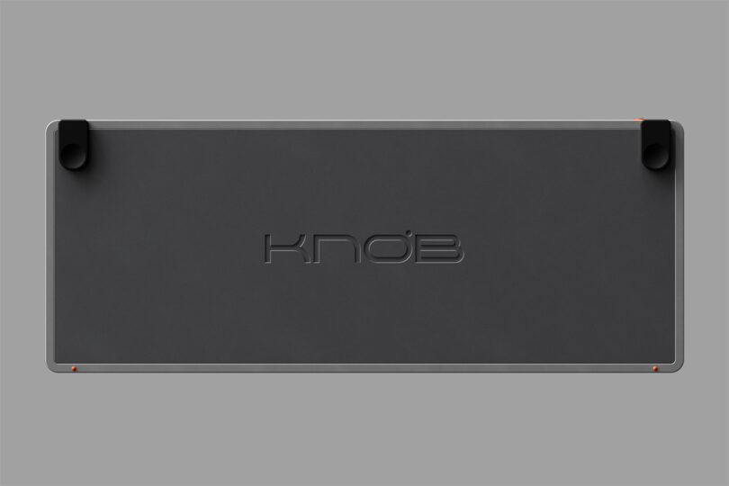 3D render of The Knob keyboard with "KNOB" debossed across the keyboard's rubber coated dark gray underside