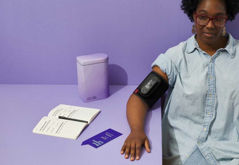 woman having blood pressure taken with kit beside her on lavender backgroun