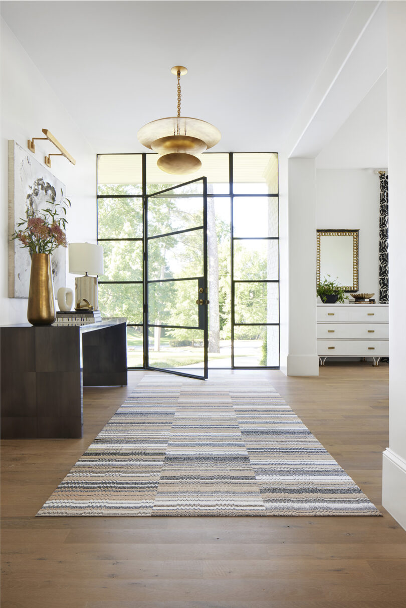 stylized space featuring large glass door and windows, a library table, and a beige carpet made of modular squares