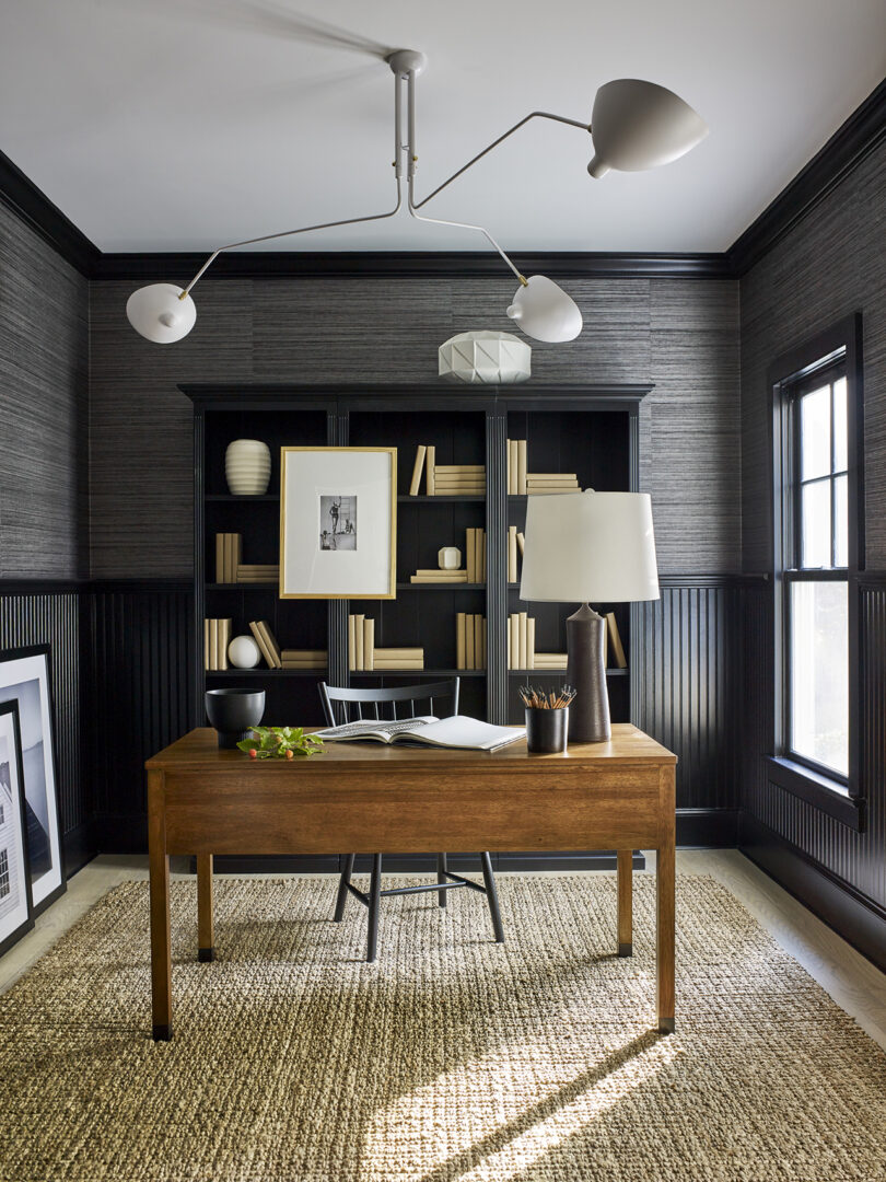 styled home office with dark walls, shelving, and a wood desk