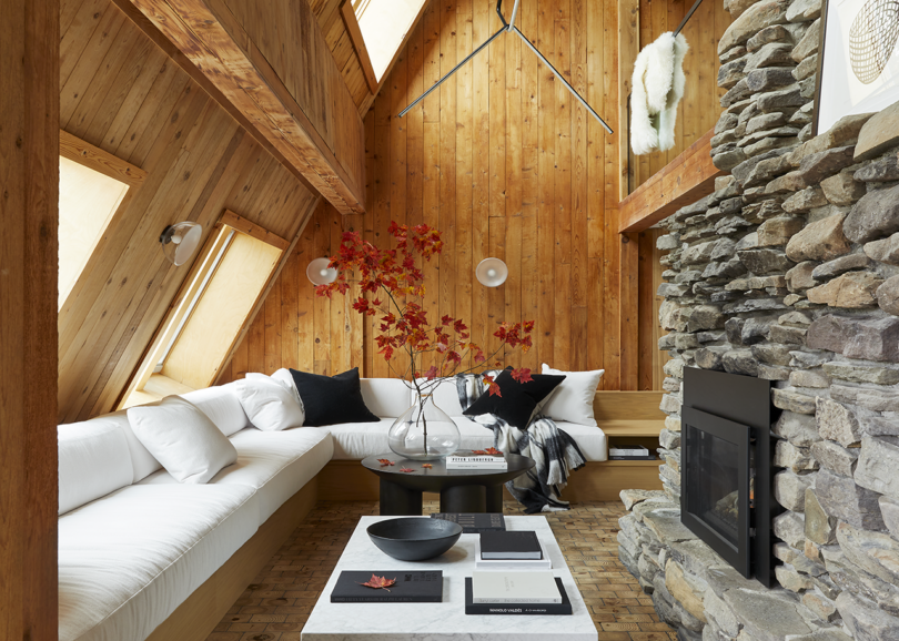 styled interior space with wood walls, a stone fireplace, a white L-shaped sofa, and a coffee table