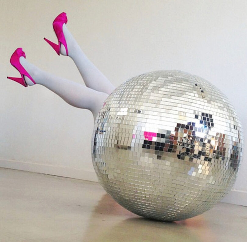 large disco ball with a pair of legs wearing pink heels sticking out of it