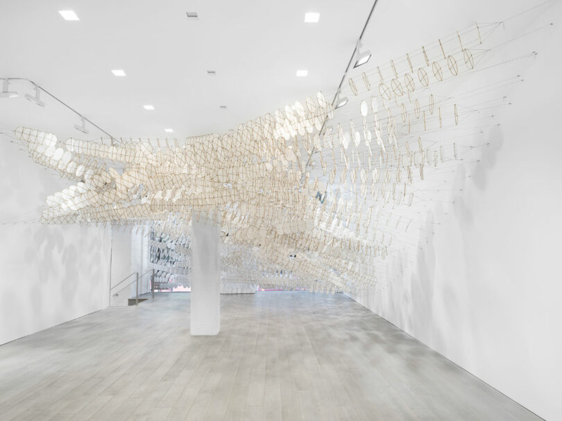 Hundreds of circular white kites stretch from wall to wall at the entrance of the gallery