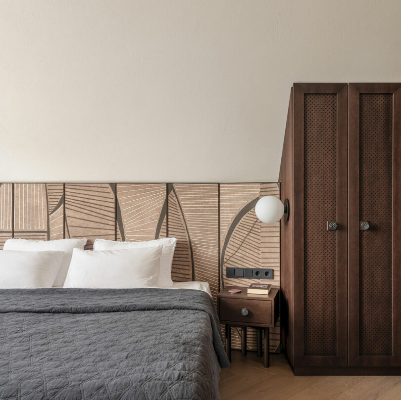 partial view of modern bedroom with dark wood cabinetry and an engraved leaf patterned headboard