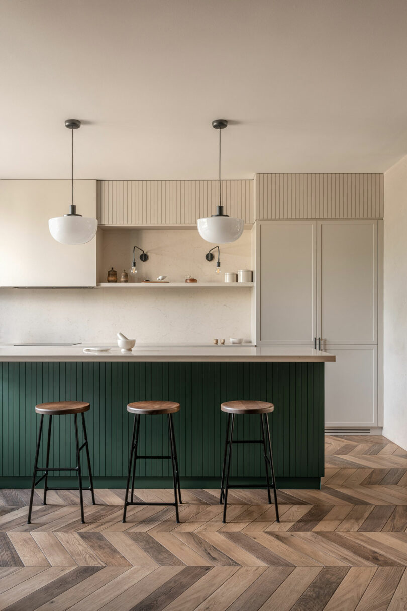 minimalist modern kitchen with dark green island and light beige cabinets