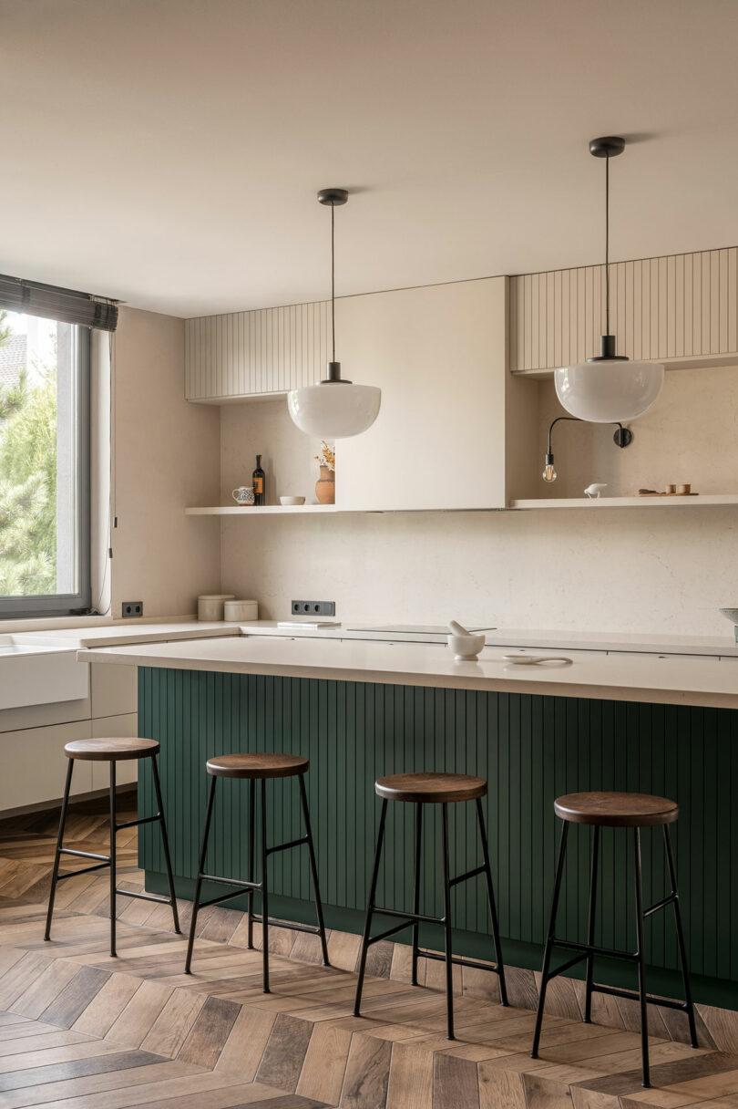 minimalist modern kitchen with dark green island and light beige cabinets