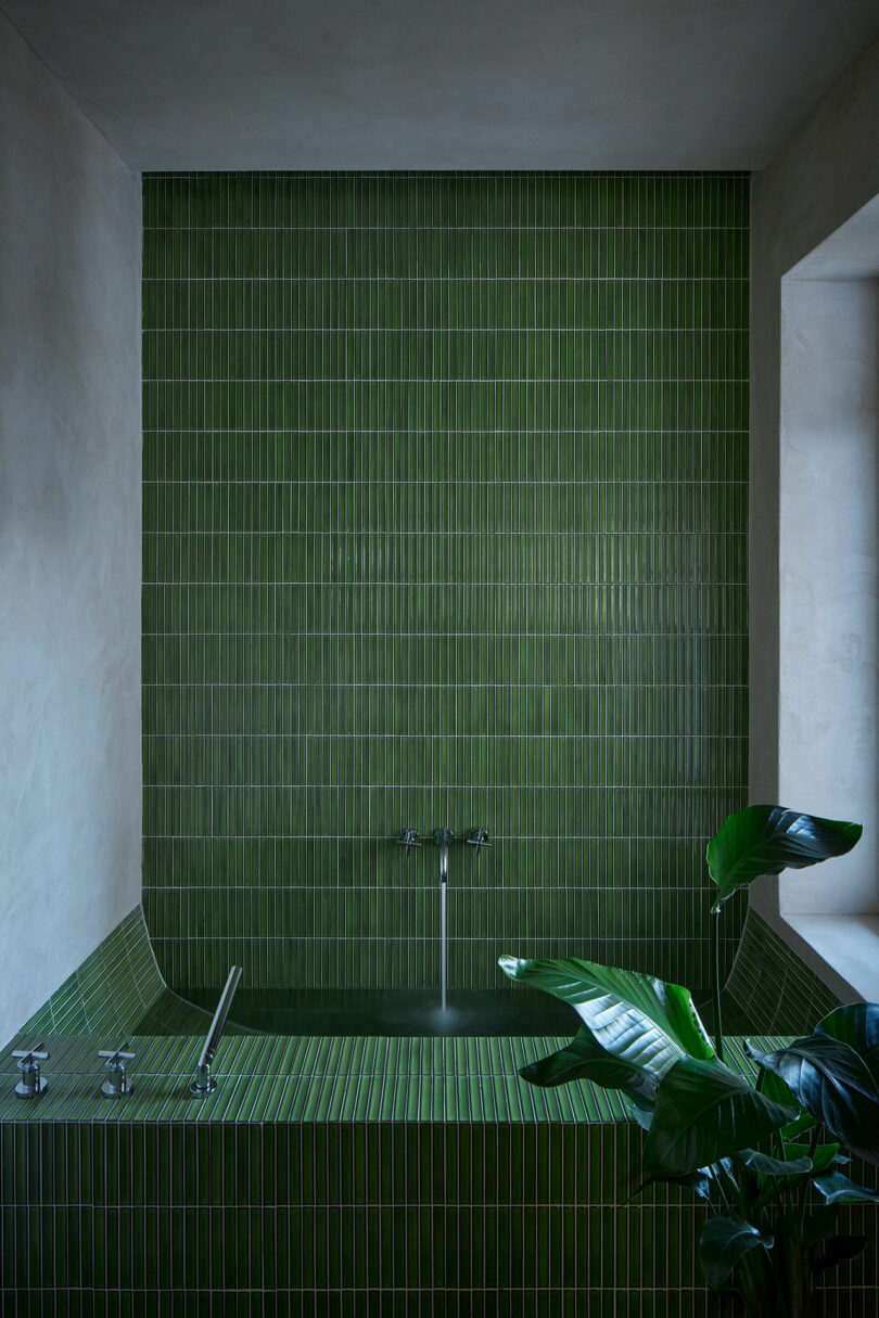 view into modern bathroom with green tiled tub and tiled wall