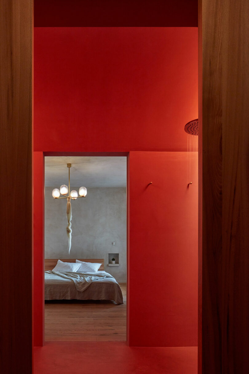 view through red bathroom into modern bedroom
