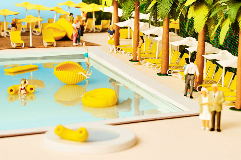 miniature scene of swimming pool with tiny pasta-shaped floats with random people
