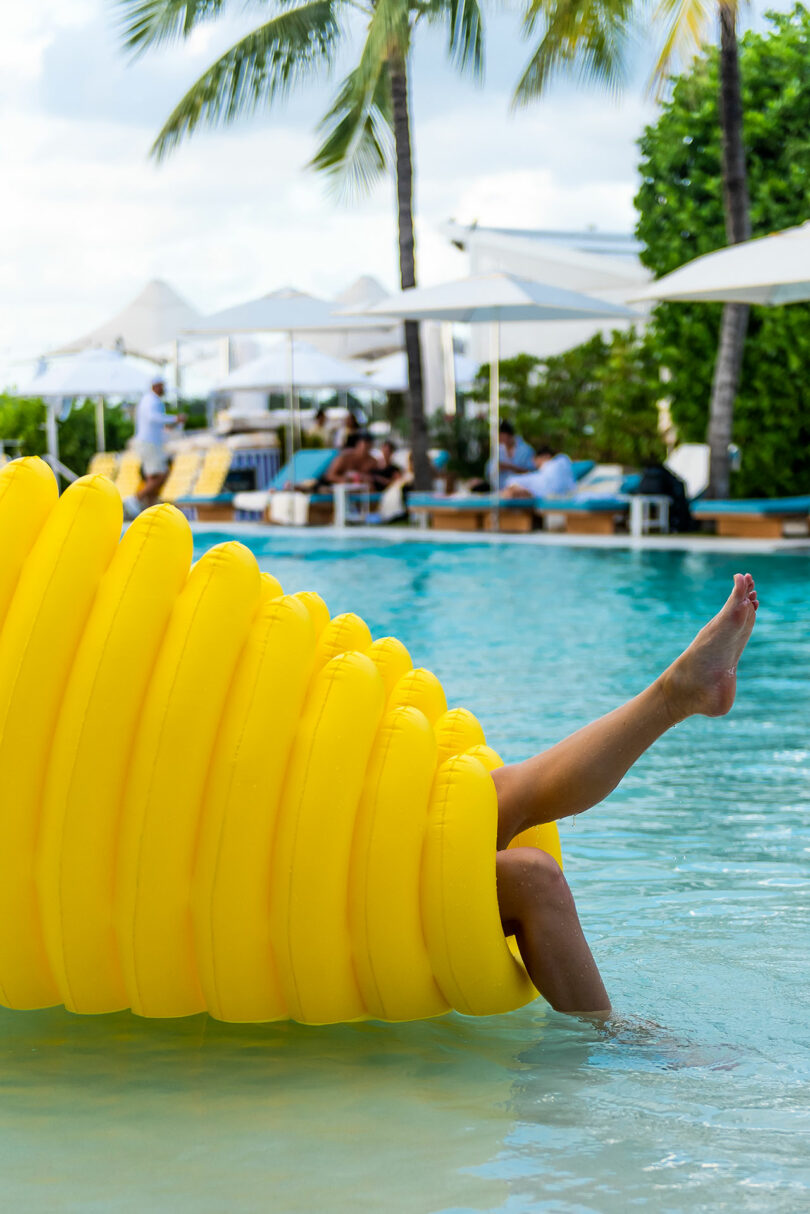 closeup of large oval ribbed pool float with legs sticking out one side while floating in pool