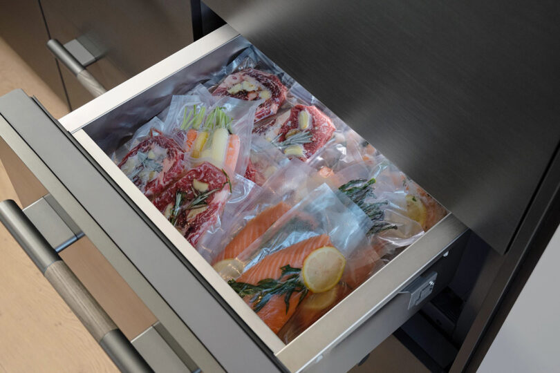 Pull out SKS refrigerator freezer drawer filled with meat and salmon for sous vide.