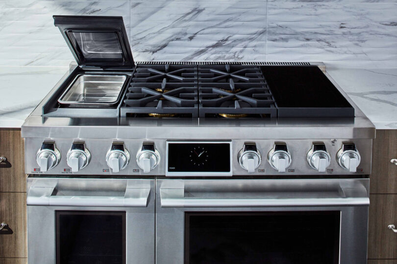 48" dual fuel induction and gas range with sous vide cooking section cover lifted up.