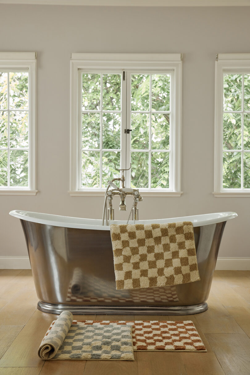 large soaking tub displaying checkered bath mats