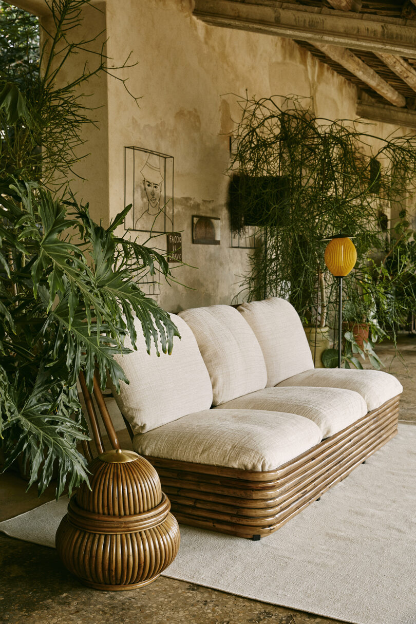 neutral toned outdoor space with cream colored sofa, green plants, and a floor lamp