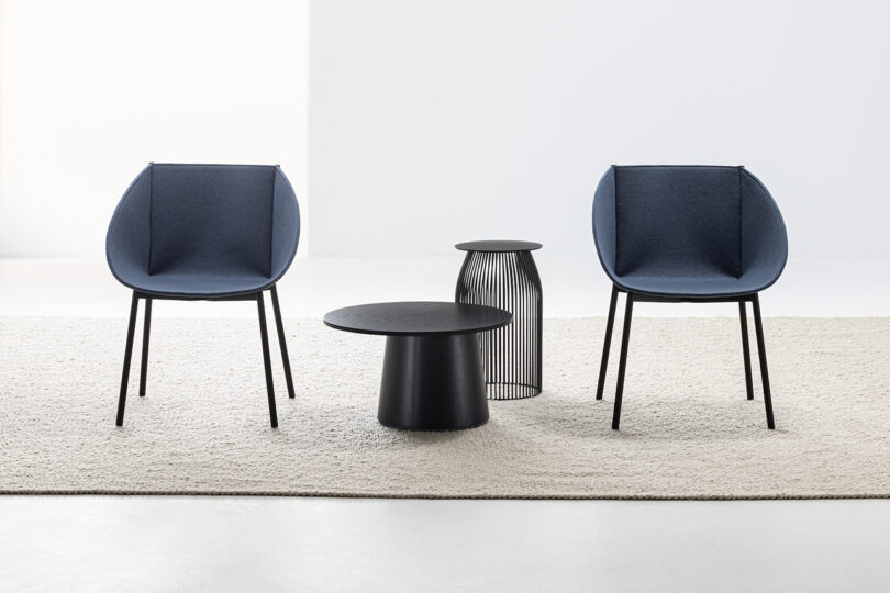 two dark grey modern armchairs with two occasional tables between them