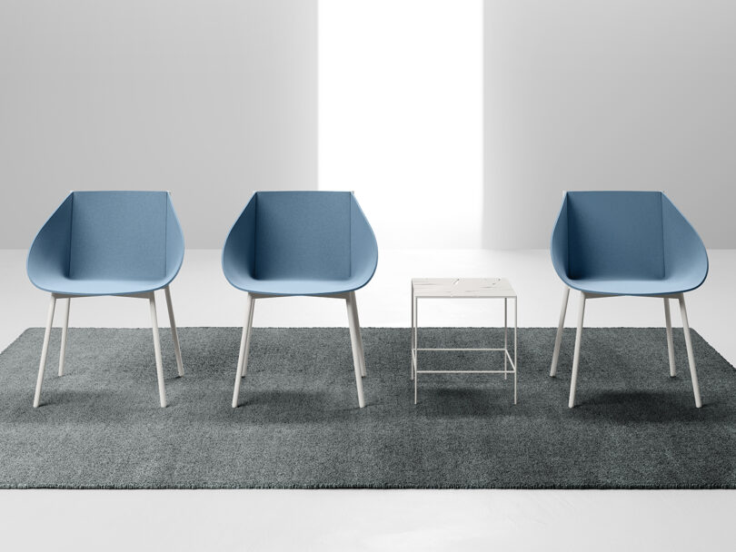 three blue-grey modern armchairs lined up with a side table