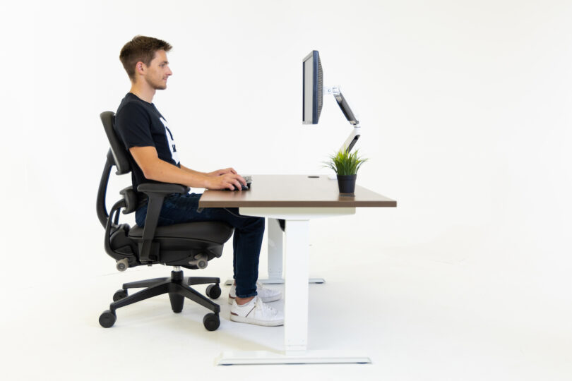 man sitting on a task chair at desk with computer