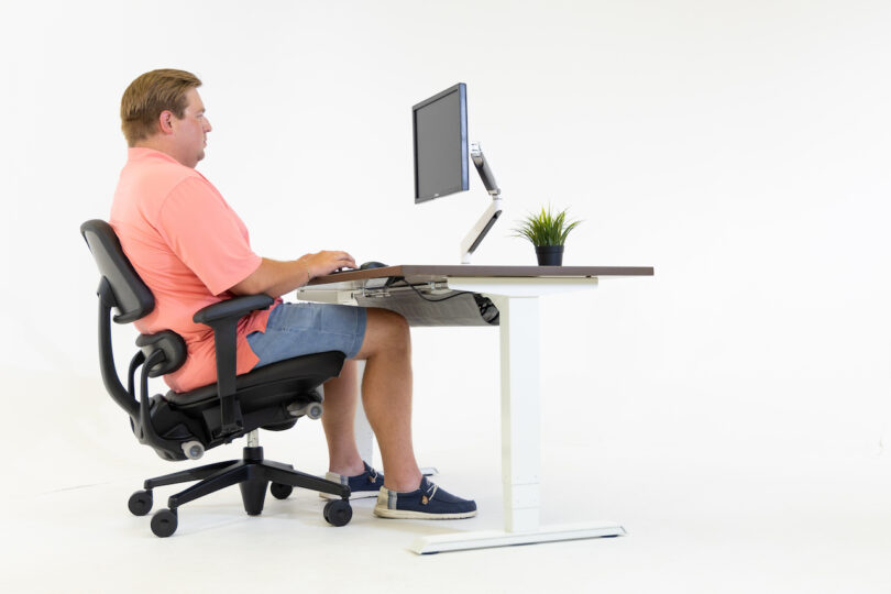 man sitting on black task chair at desk with computer