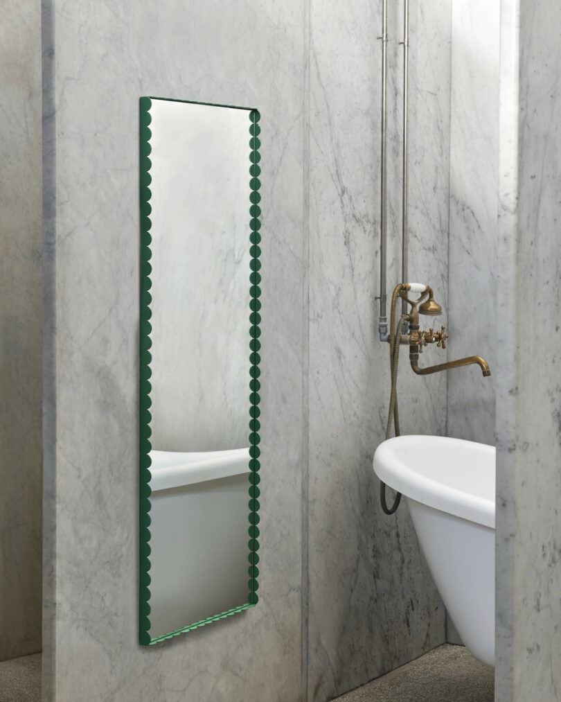 long green scalloped mirror in marble bathroom