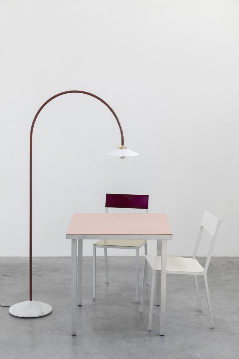 burgundy minimalist lamp next to chairs and peach colored table