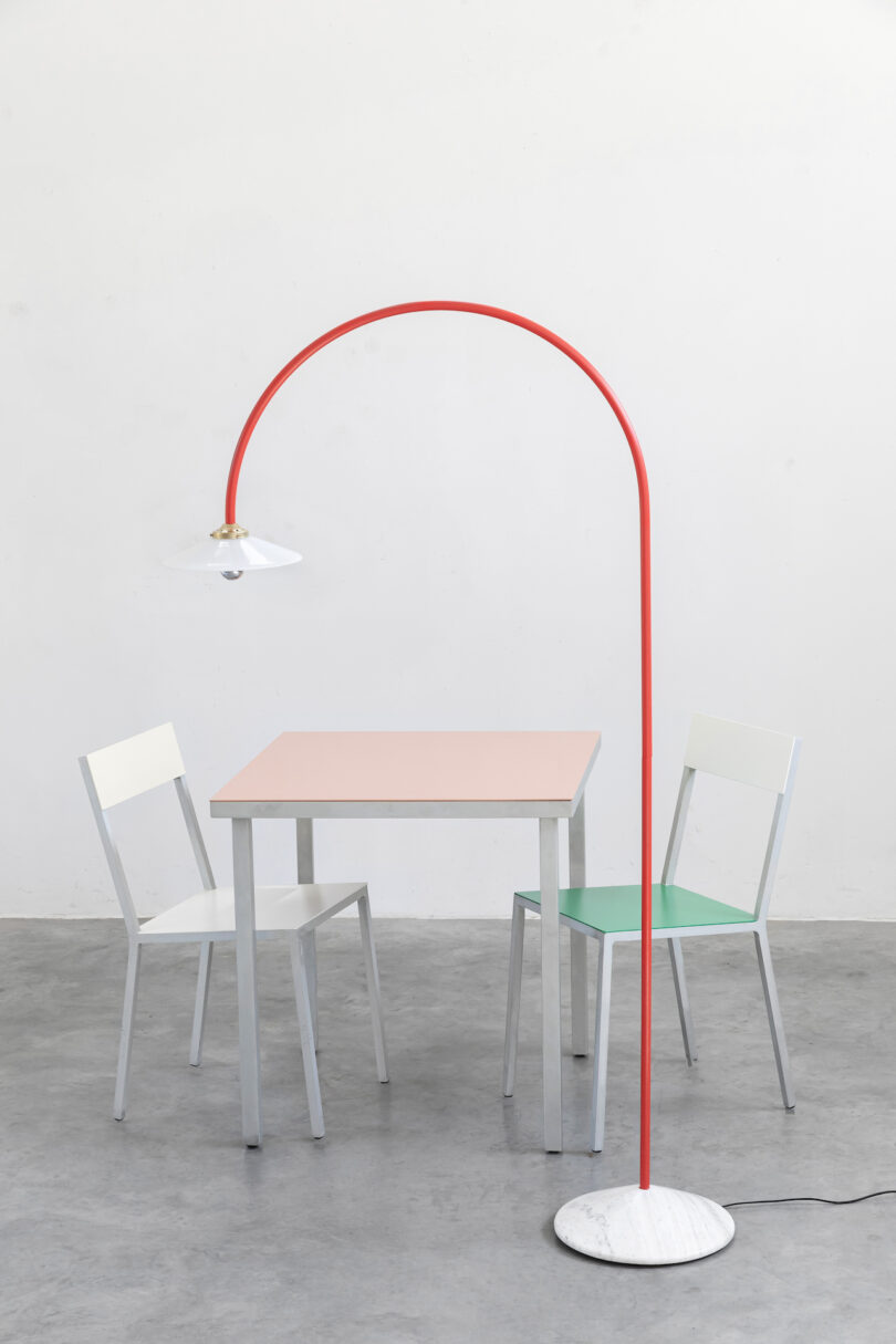 red minimalist lamp next to chairs and peach colored table