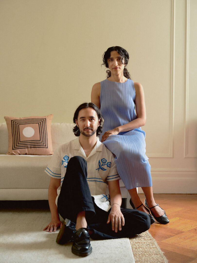 man sitting on the floor with woman in blue dress sitting on sofa