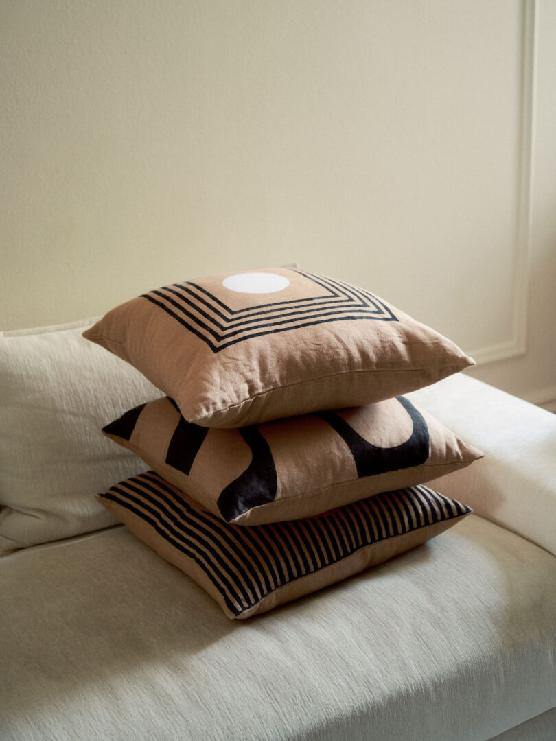 three monochromatic pillows stacked on top of each other on white sofa